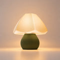 Abajur de mesa Alba aceso, com cúpula branca plissada em origami e base verde oliva