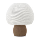 Abajur de mesa com cúpula branca em formato de cogumelo com nervuras em espiral e base canelada marrom, em fundo branco